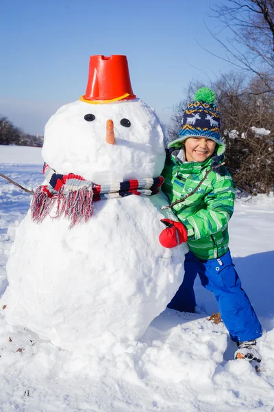 Pojke med en snögubbe — Stockfoto