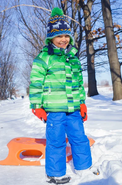 Bambino che si diverte con la slitta nel parco invernale — Foto Stock