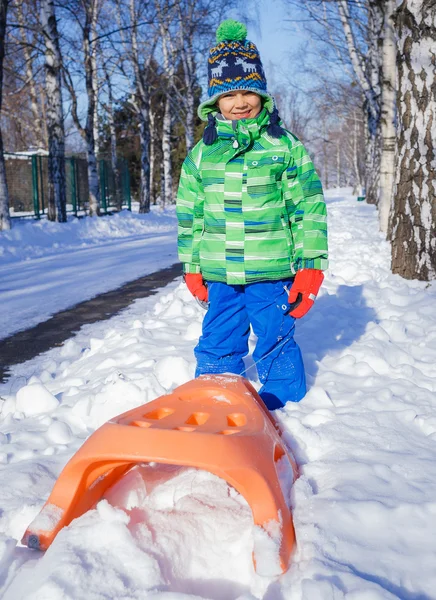 Menino se divertindo com trenó no parque de inverno — Fotografia de Stock