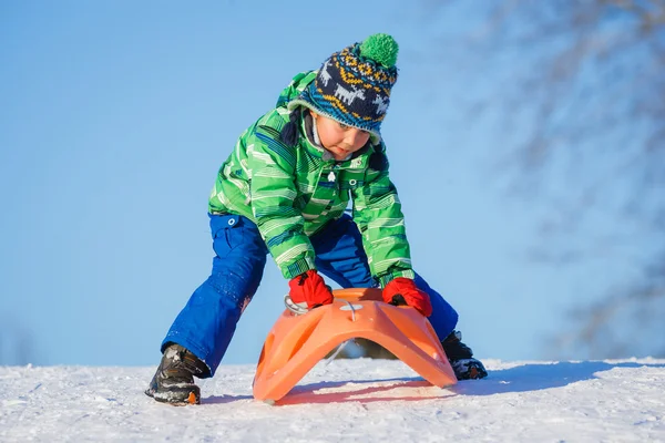 Niño divirtiéndose con trineo en el parque de invierno — Foto de Stock