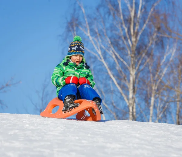 Мальчик веселится с санями в зимнем парке — стоковое фото