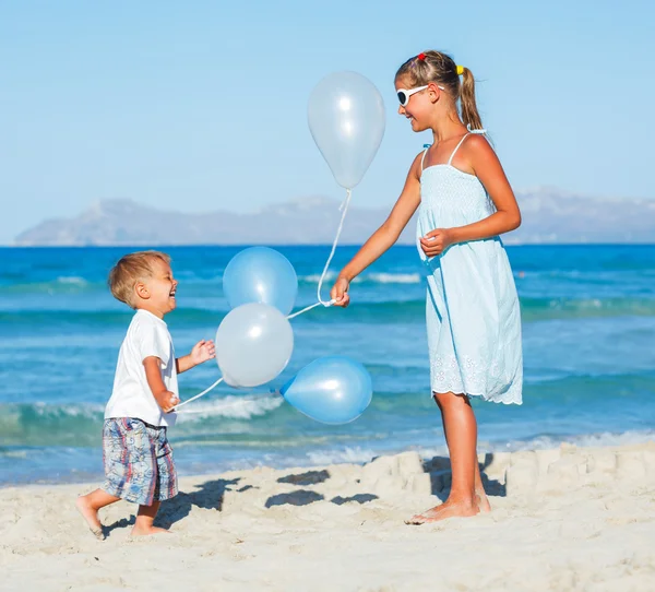 Barn med ballonger på stranden — Stockfoto