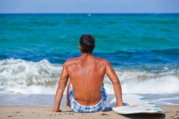 Człowiek z jego deskę surfingową na plaży — Zdjęcie stockowe