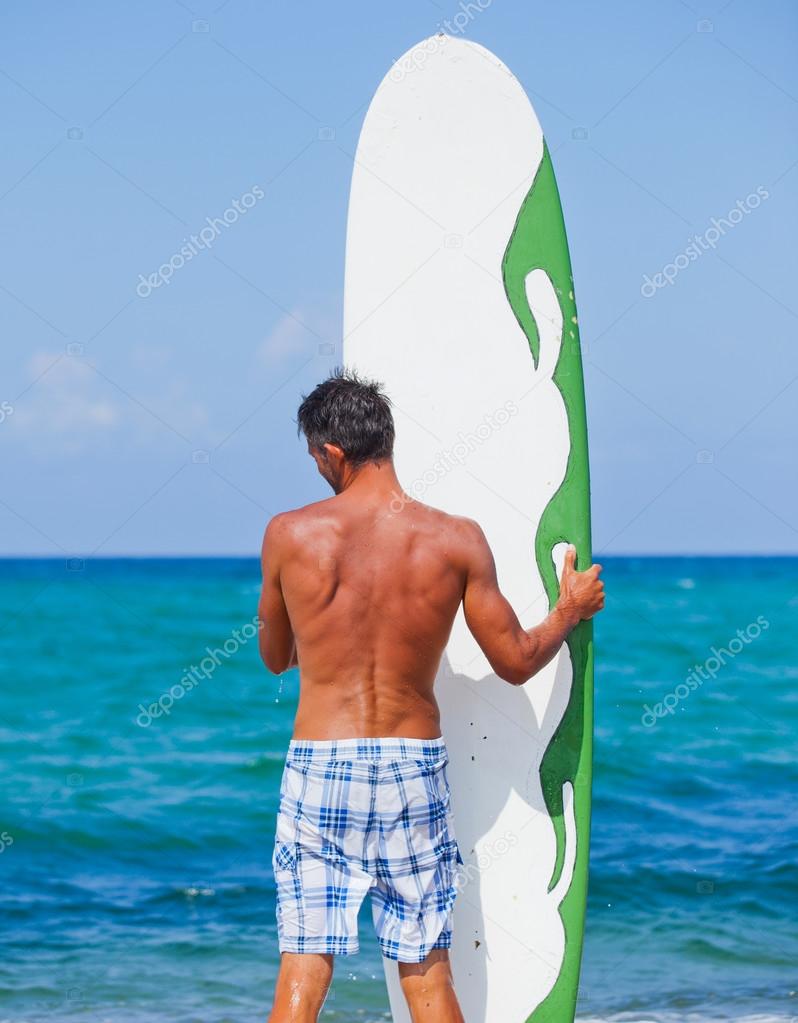 Man with his surfboard on the beach