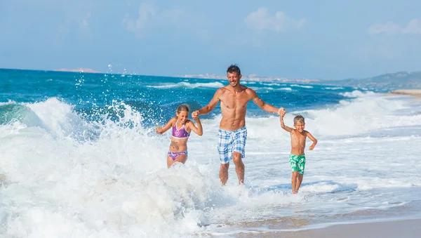 Vader en kinderen spelen op het strand — Stockfoto