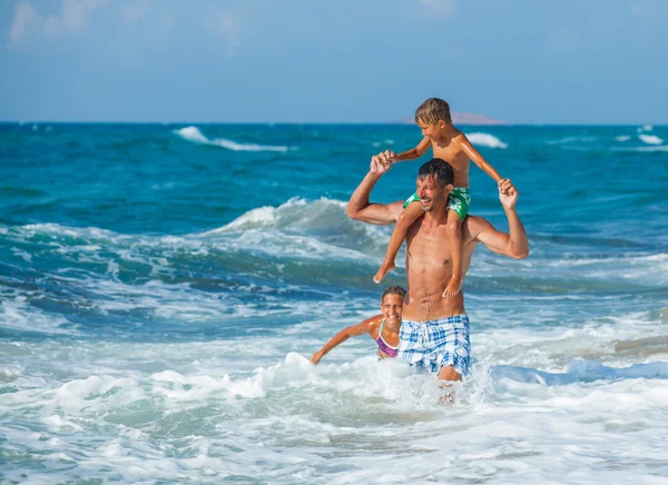 Vader en kinderen spelen in de zee — Stockfoto