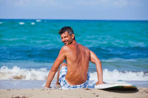 Człowiek z jego deskę surfingową na plaży — Zdjęcie stockowe