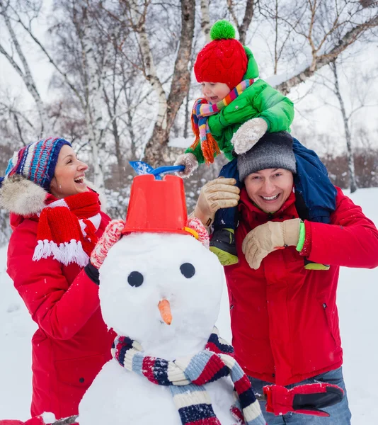 Familie mit einem Schneemann — Stockfoto