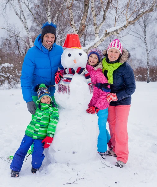 Familie met een sneeuwpop — Stockfoto