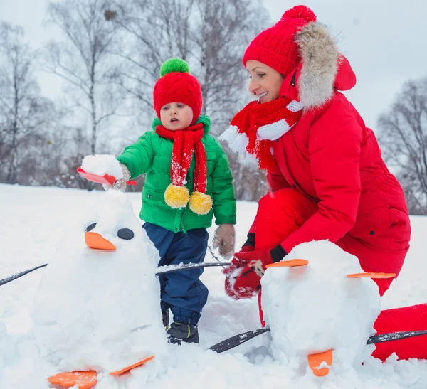 Jongen en zijn moeder met een sneeuwpop — Stockfoto