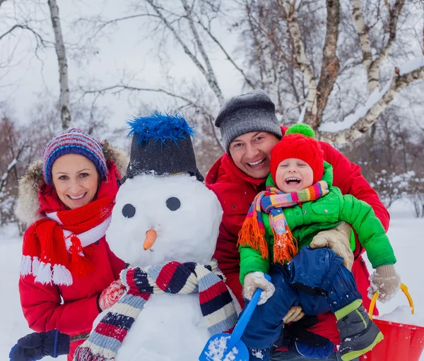 Familia con un muñeco de nieve —  Fotos de Stock