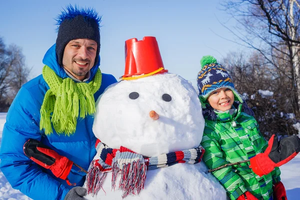 Junge und sein Vater mit einem Schneemann — Stockfoto