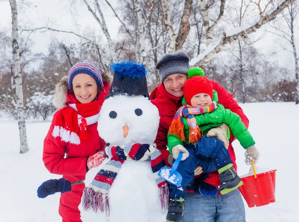 Familj med en snögubbe — Stockfoto