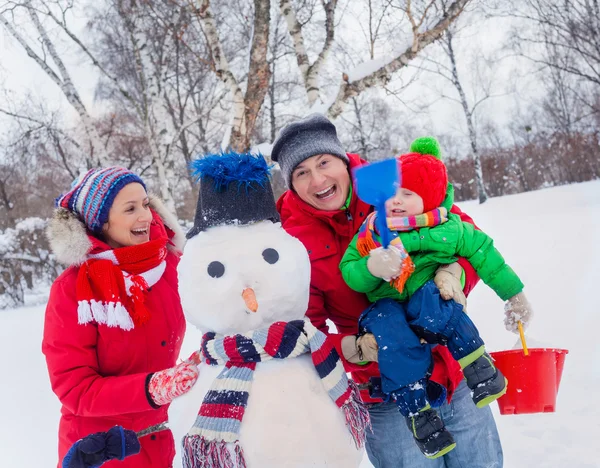 Família com um boneco de neve — Fotografia de Stock