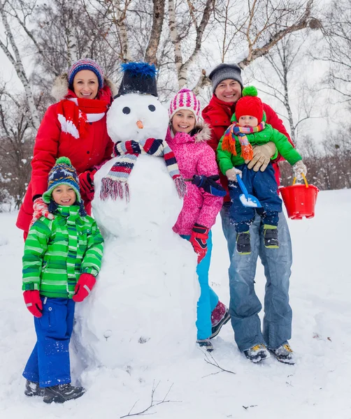 Familj med en snögubbe — Stockfoto