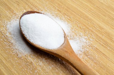 Bambu kesme tahtasında ahşap kaşıkta yemek pişirmede kullanılan masa tuzu.