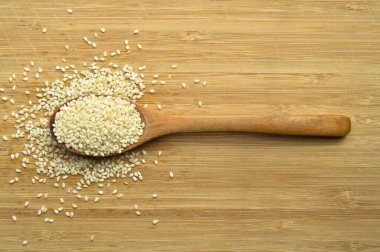 Organik taze susam tohumları, bambu kesme tahtasındaki tahta kaşıkta.