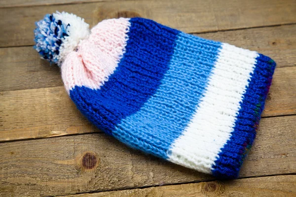 木制背景的手工毛织冬季蓝白相间的帽子 — 图库照片