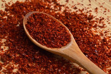 Bambu kesme tahtasındaki ahşap kaşıkta kurutulmuş kırmızı biber.