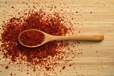 Bambu kesme tahtasındaki ahşap kaşıkta kurutulmuş kırmızı biber.