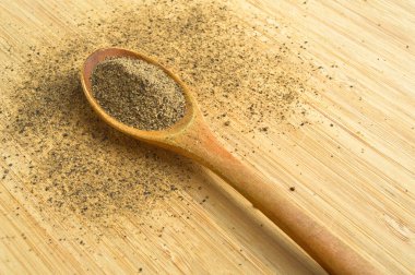 Ahşap bambu kesme tahtasının üzerinde kaşık içinde Aromatik ve taze kara biber tozu.