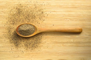 Ahşap bambu kesme tahtasının üzerinde kaşık içinde Aromatik ve taze kara biber tozu.