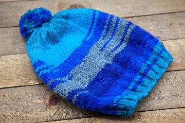 Ahşap arka planda el yapımı yün örülmüş kış şapkası.