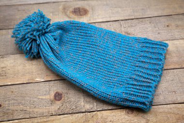 Ahşap arka planda el yapımı yün örülmüş kış şapkası.