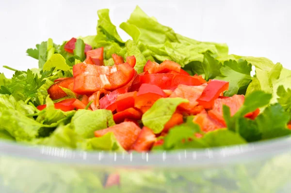 Taze çiğ yeşil sağlıklı marul salatası cam tabakta, beyaz arka planda izole edilmiş.