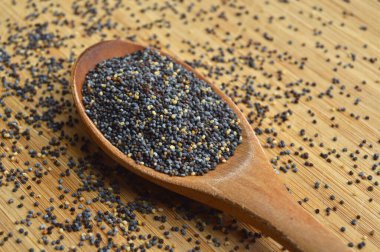 Taze ve ince taneli kurutulmuş haşhaş tohumları bambu kesme tahtasındaki tahta kaşıkta.