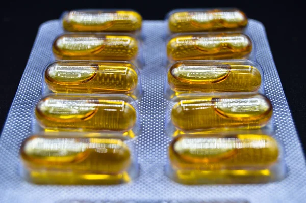 Tabletki Owalne Żółte Olej Rybny Pakowane Izolowane Czarnym Tle Tabletki — Zdjęcie stockowe