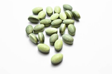 Beyaz arka planda izole edilmiş yeşil oval tablet haplar, tıbbi oval haplar