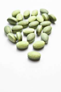 Beyaz arka planda izole edilmiş yeşil oval tablet haplar, tıbbi oval haplar