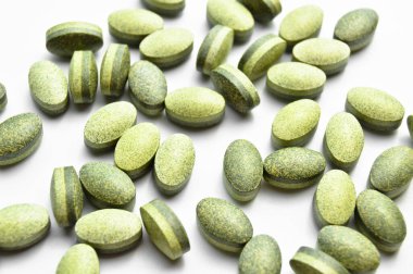 Beyaz arka planda izole edilmiş yeşil oval tablet haplar, tıbbi oval haplar