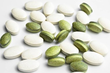 Beyaz arka planda izole edilmiş beyaz ve yeşil oval tablet haplar, tıbbi oval haplar