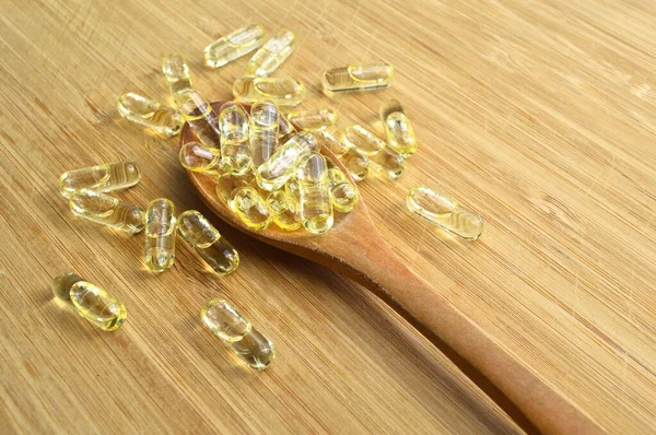 Pillole Ovali Olio Pesce Giallo Cucchiaio Legno Sul Tagliere Bambù — Foto Stock