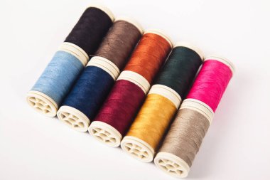 Farklı renklerde dikmek için iplik makaraları ve bobinleri, beyaz arka planda izole edilmiş.