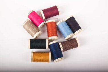 Farklı renklerde dikmek için iplik makaraları ve bobinleri, beyaz arka planda izole edilmiş.