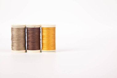 Farklı renklerde dikmek için iplik makaraları ve bobinleri, beyaz arka planda izole edilmiş.