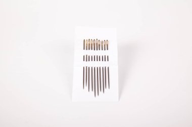 Dikiş için çeşitli boyutlarda çelik dikiş iğneleri, beyaz arka planda izole edilmiş.