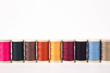 Farklı renklerde dikmek için iplik makaraları ve bobinleri, beyaz arka planda izole edilmiş.