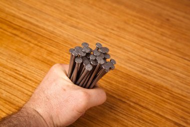 Metal demir ceviz ağacının üzerinde sivri uçlu çivi elinde duruyor, ahşap zemin üzerinde izole.