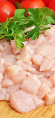 Taze çiğ tavuk eti göğüs parçaları, pişirmeye hazır, domates ve maydanozlu.