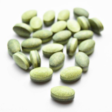Beyaz arka planda izole edilmiş yeşil oval tablet haplar, tıbbi oval haplar