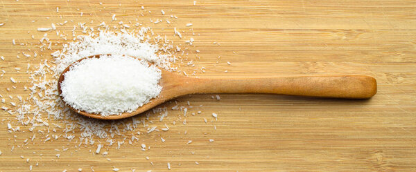 Свежий и питательный кокос в деревянной ложке на бамбуковой доске