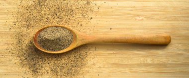 Ahşap bambu kesme tahtasının üzerinde kaşık içinde Aromatik ve taze kara biber tozu.