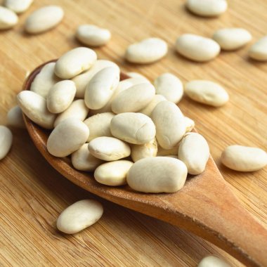 Kurumuş organik fasulyeler bambu kesme tahtasının üzerinde tahta kaşıkta.