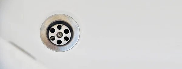 Drain in a white clean sink, background, close-up