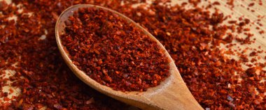 Bambu kesme tahtasındaki ahşap kaşıkta kurutulmuş kırmızı biber.