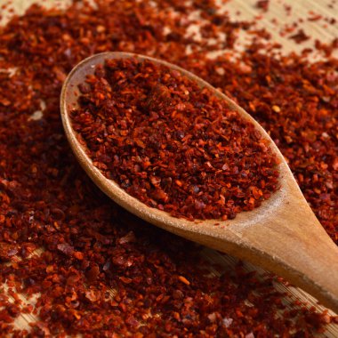 Bambu kesme tahtasındaki ahşap kaşıkta kurutulmuş kırmızı biber.